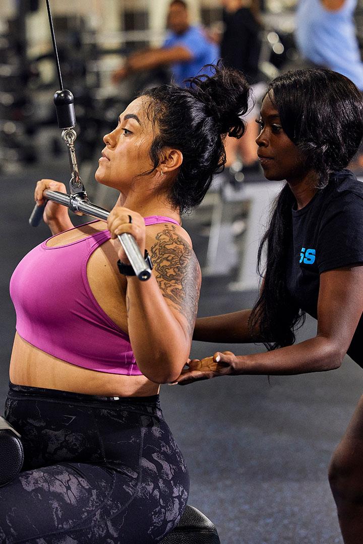 Trainer helping a woman with a lat pulldown exercise