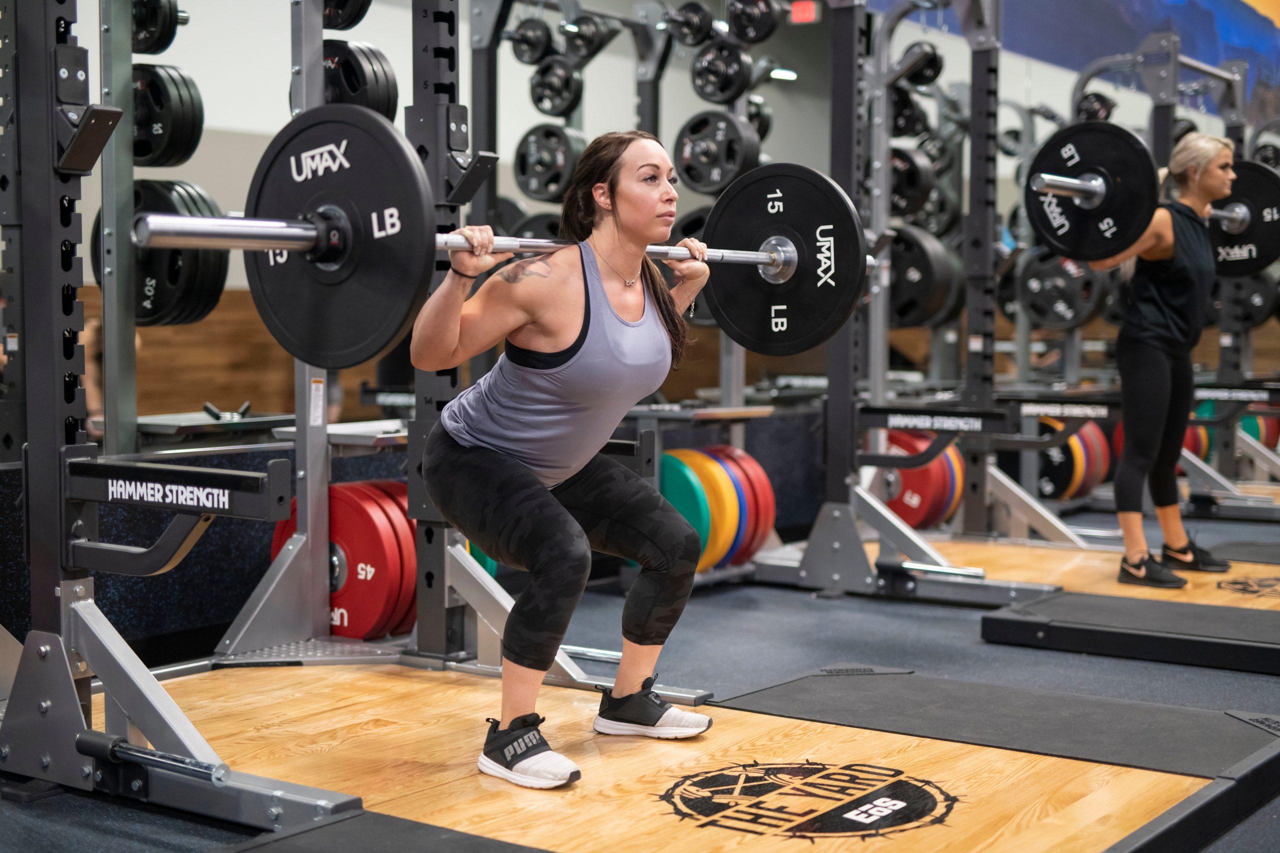 athletic eos gym member barbell squatting