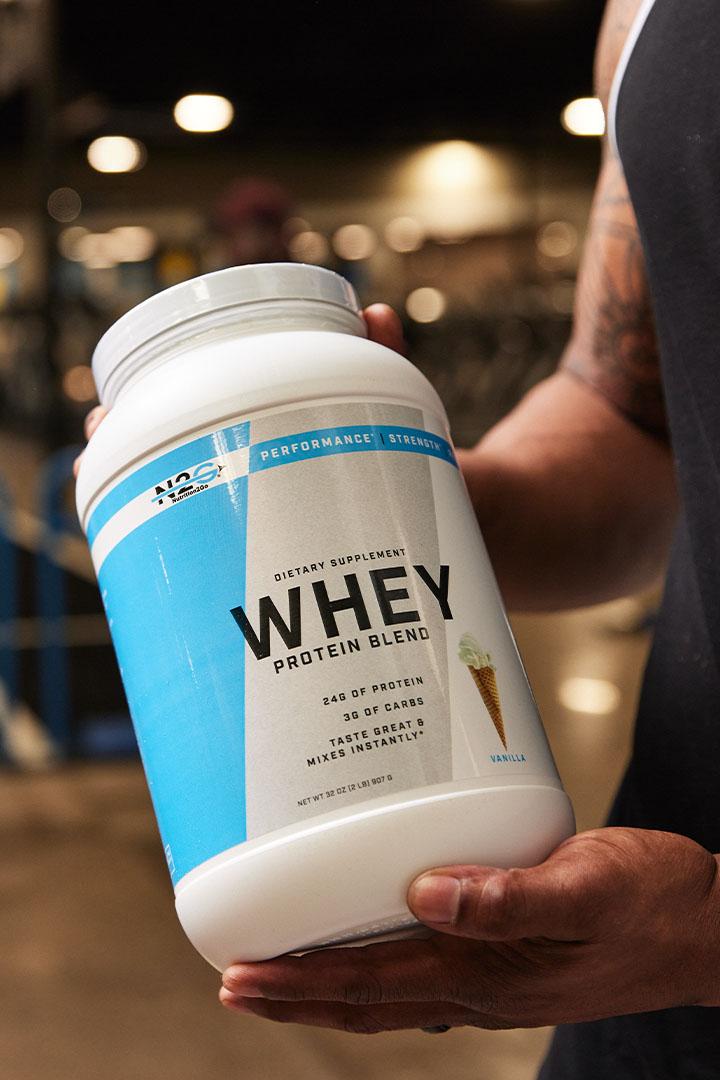 Person holding a container of whey protein supplement