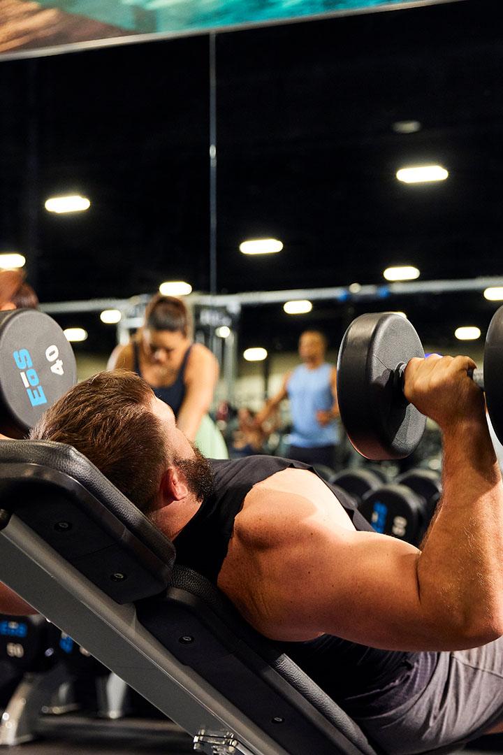 Man performing an incline dumbbell press at the gym