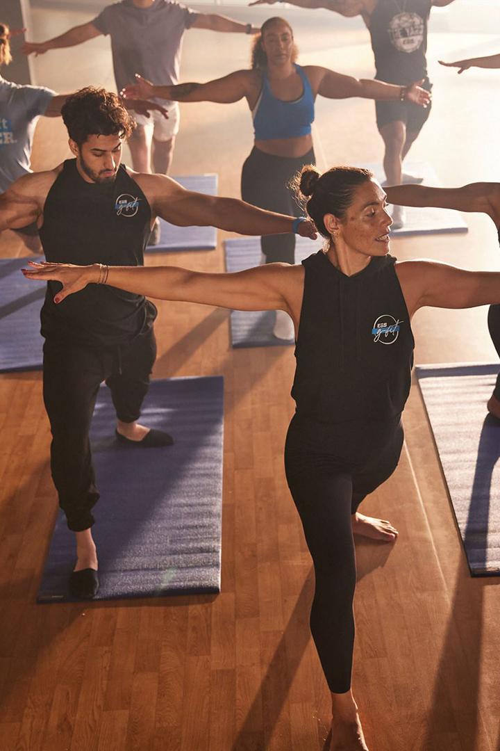 dynamic shot of a group of eos gym members doing a pose in a modern studio with yoga mats