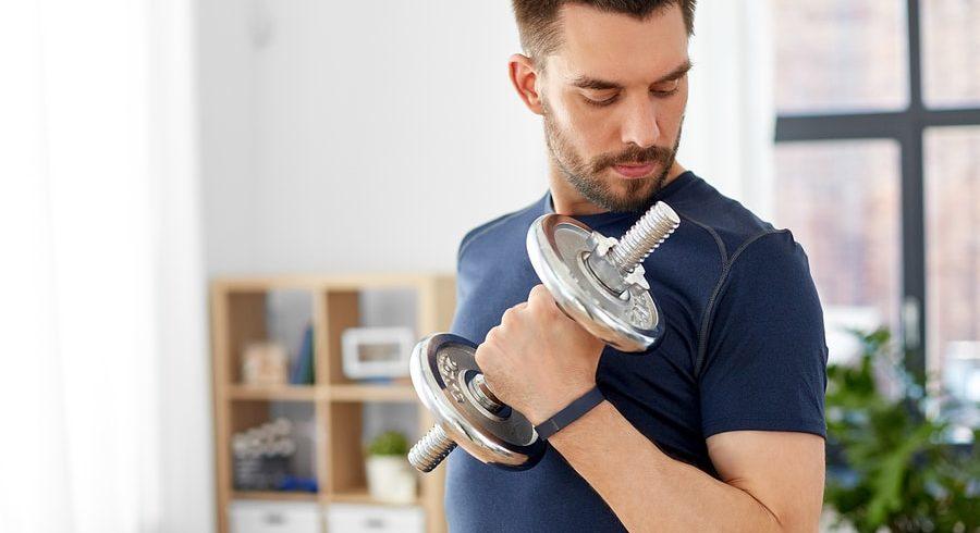 Man lifting a dumbbell while looking at his bicep