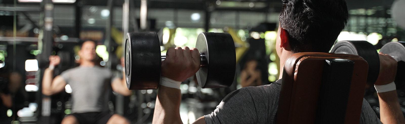 man in gym doing upper body free weight exercises