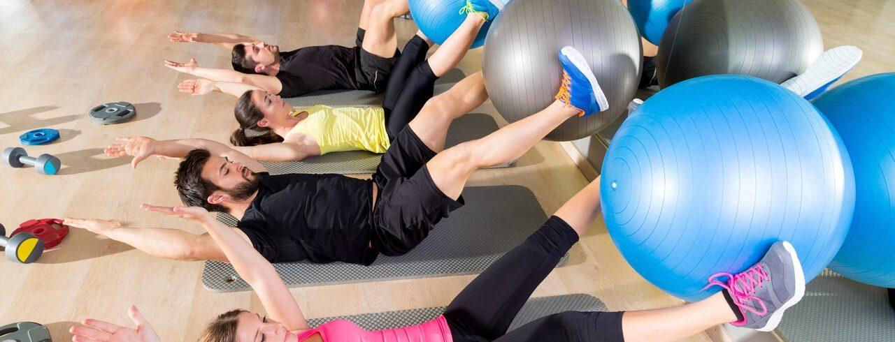 a group of athletic eos gym members performing a core workout with a stability ball