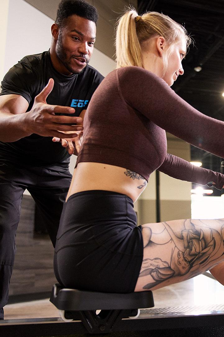 Trainer coaching a woman using a rowing machine in the gym