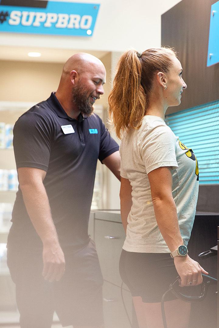 Trainer helping a member with fitness equipment