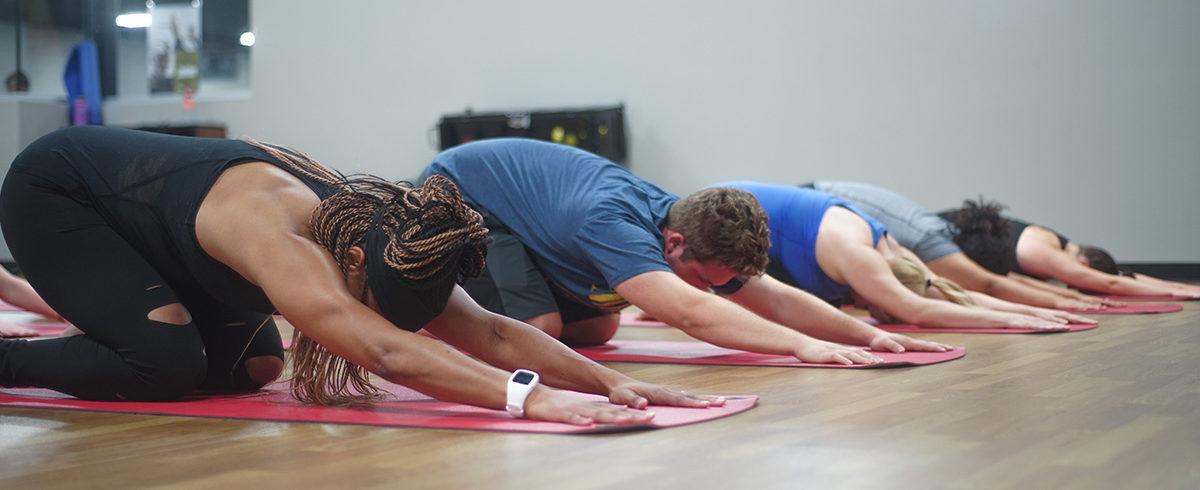 group of eos gym members in Child's Pose on yoga maps