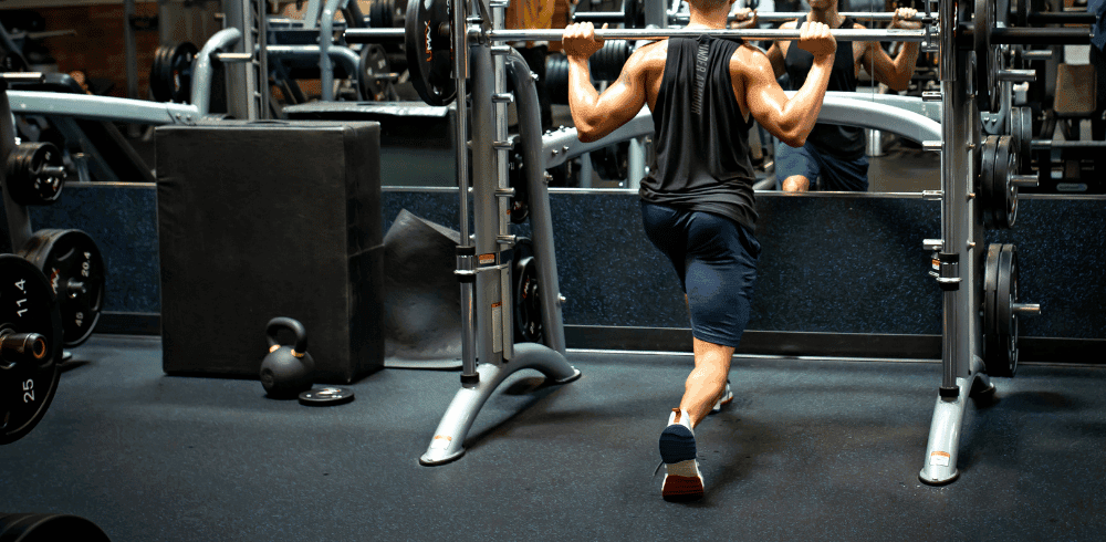 athletic eos gym member performing barbell lunches on smith machine