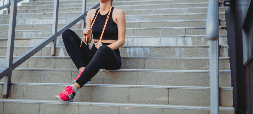 athletic person wearing compressing clothing sitting on stairs