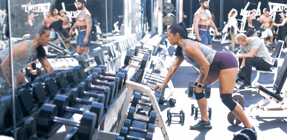 a eos gym full of athletic member performing a verity of dumbbell exercises 