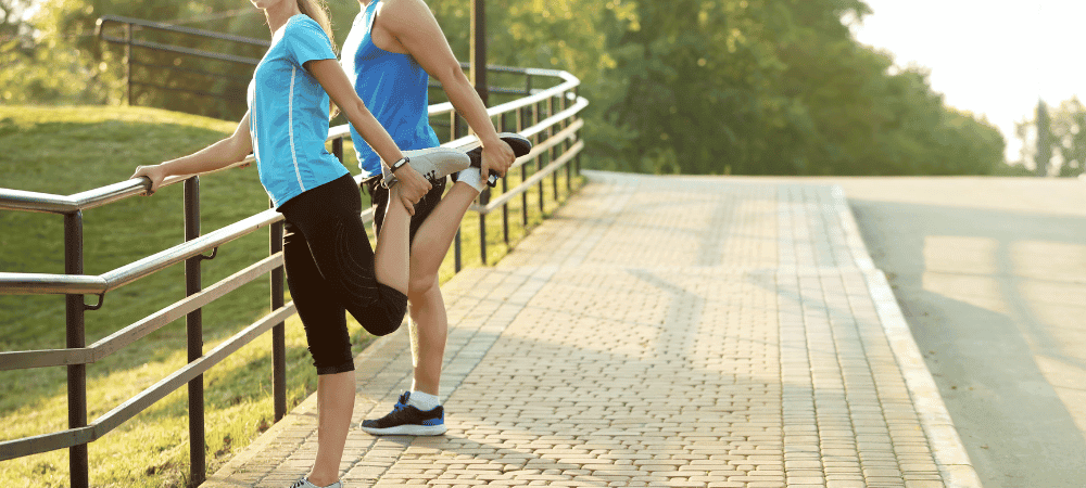 two athletic people doing warm-up and cool-down exercises outside in a sunny park