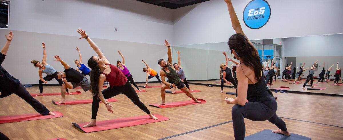 athletic eos instructor leading a group of members in yoga in a modern studio 